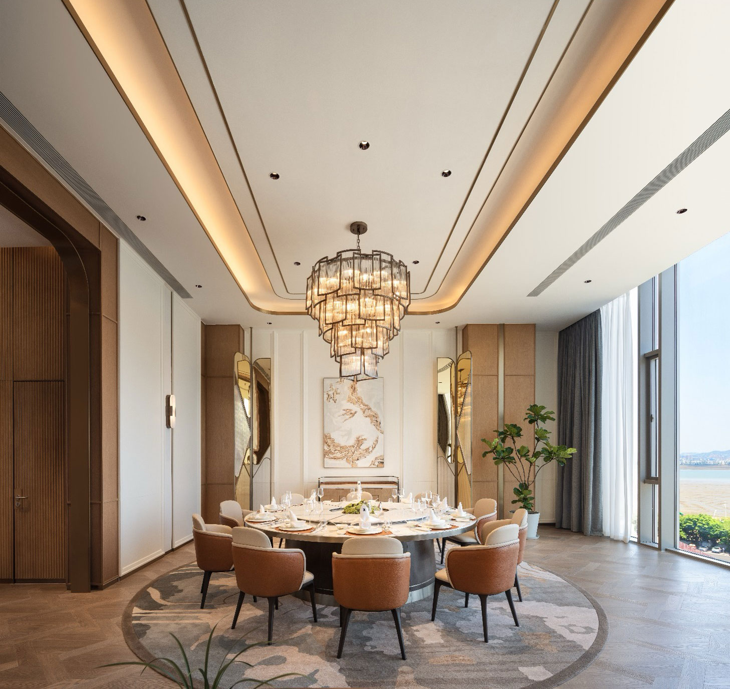 Elegant dining room with a large round table, set for a meal. A stunning chandelier hangs above, with tall windows offering a scenic view. Relaxed atmosphere.