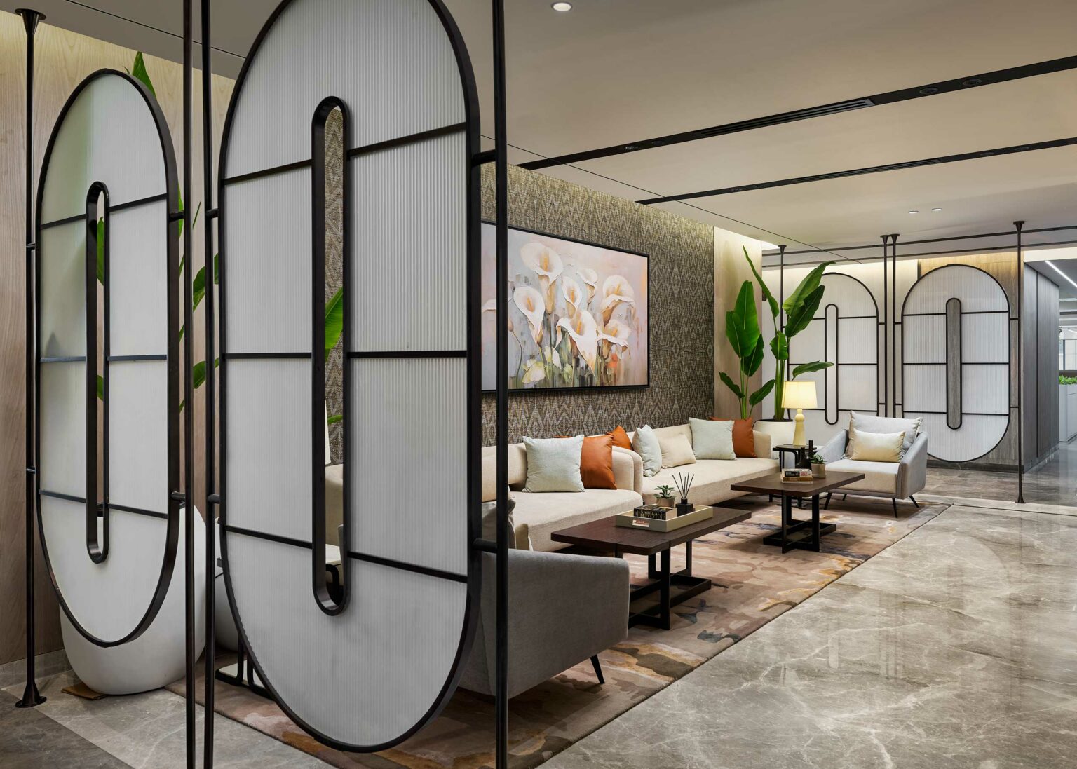Modern lobby with sleek furniture, large geometric room dividers, and a neutral color palette. Features a cozy seating area and floral artwork.