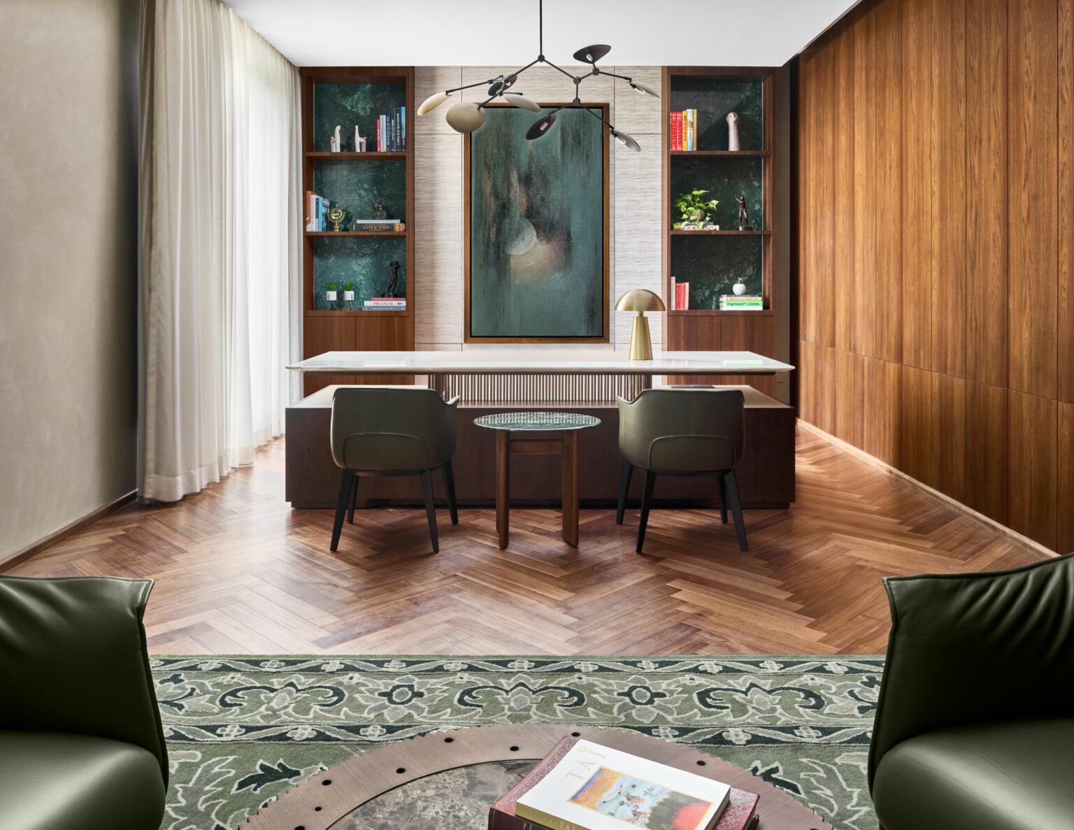 Sophisticated home office with a wooden desk, green chairs, and bookshelves. A large abstract painting adds elegance, while natural light enhances warmth.